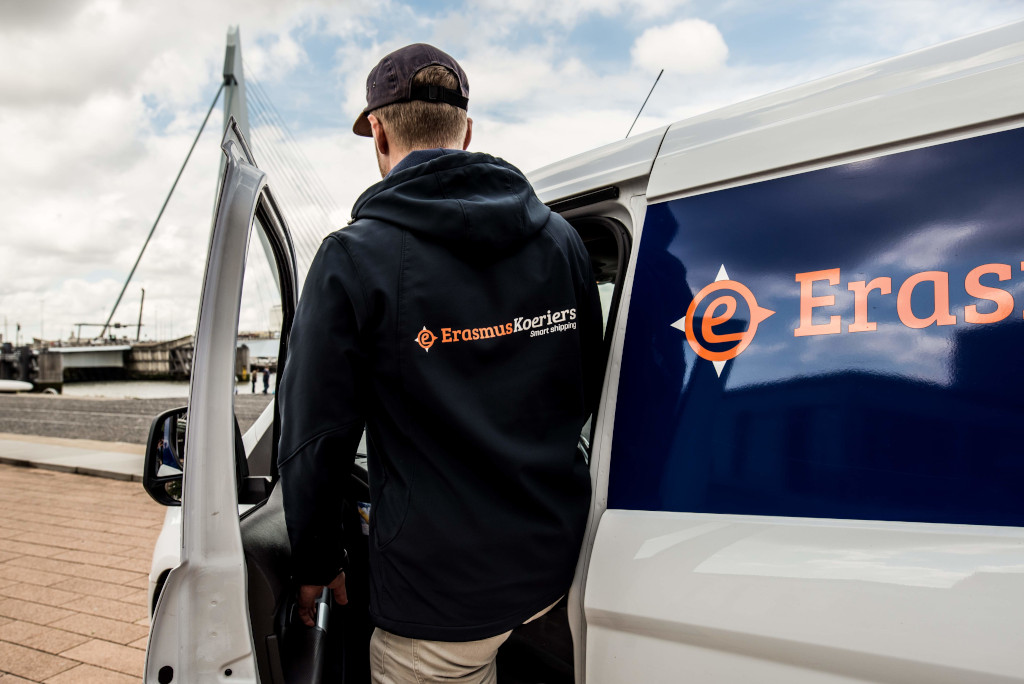 Koerier van Erasmus Koeriers stapt in auto van Erasmus Koeriers voor de Erasmusburg in Rotterdam. Spoedkoerier diensten Erasmus Koeriers