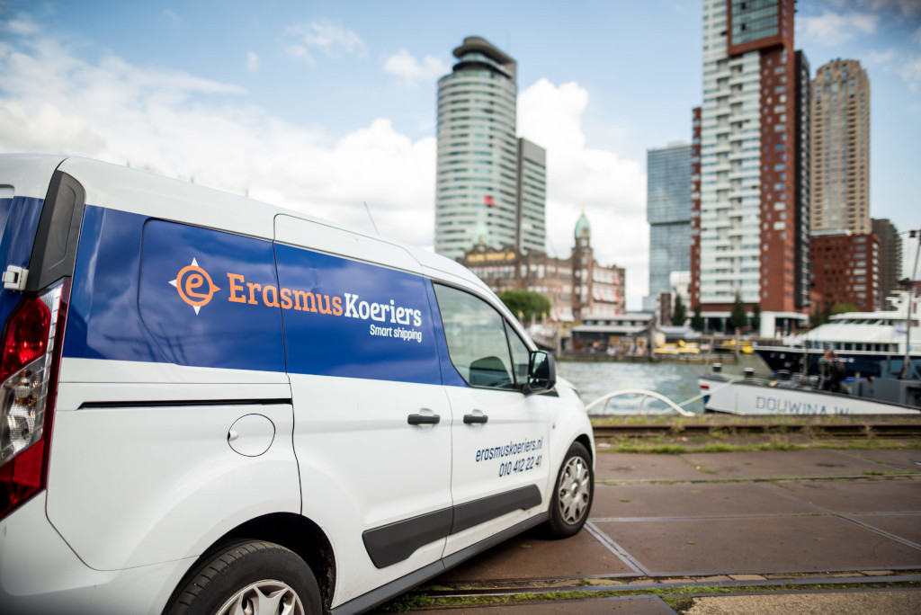 Bestelauto van Erasmus Koeriers staat op de foto met het centrum van Rotterdam op de achtergrond. Budget koeriers diensten