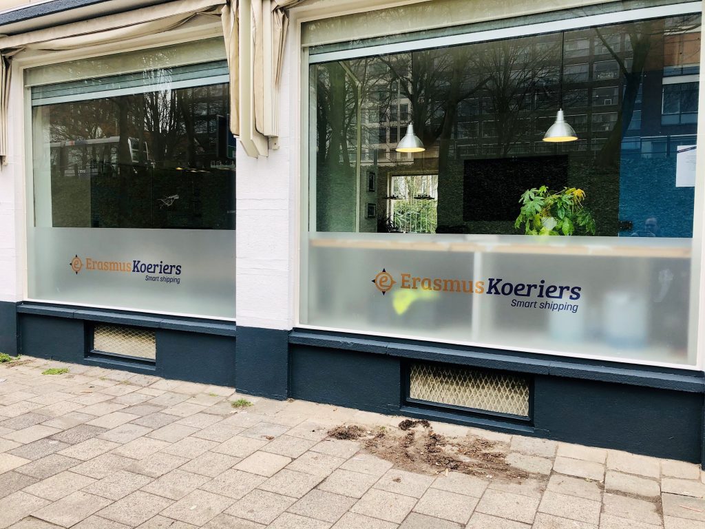 Voorgevel van Erasmus Koeriers kantoor met twee grote ramen met daarop het logo van Erasmus Koeriers